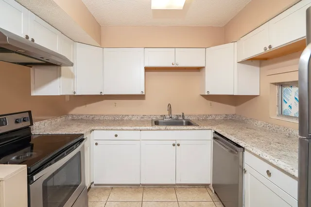a kitchen with granite countertop a sink stove and cabinets