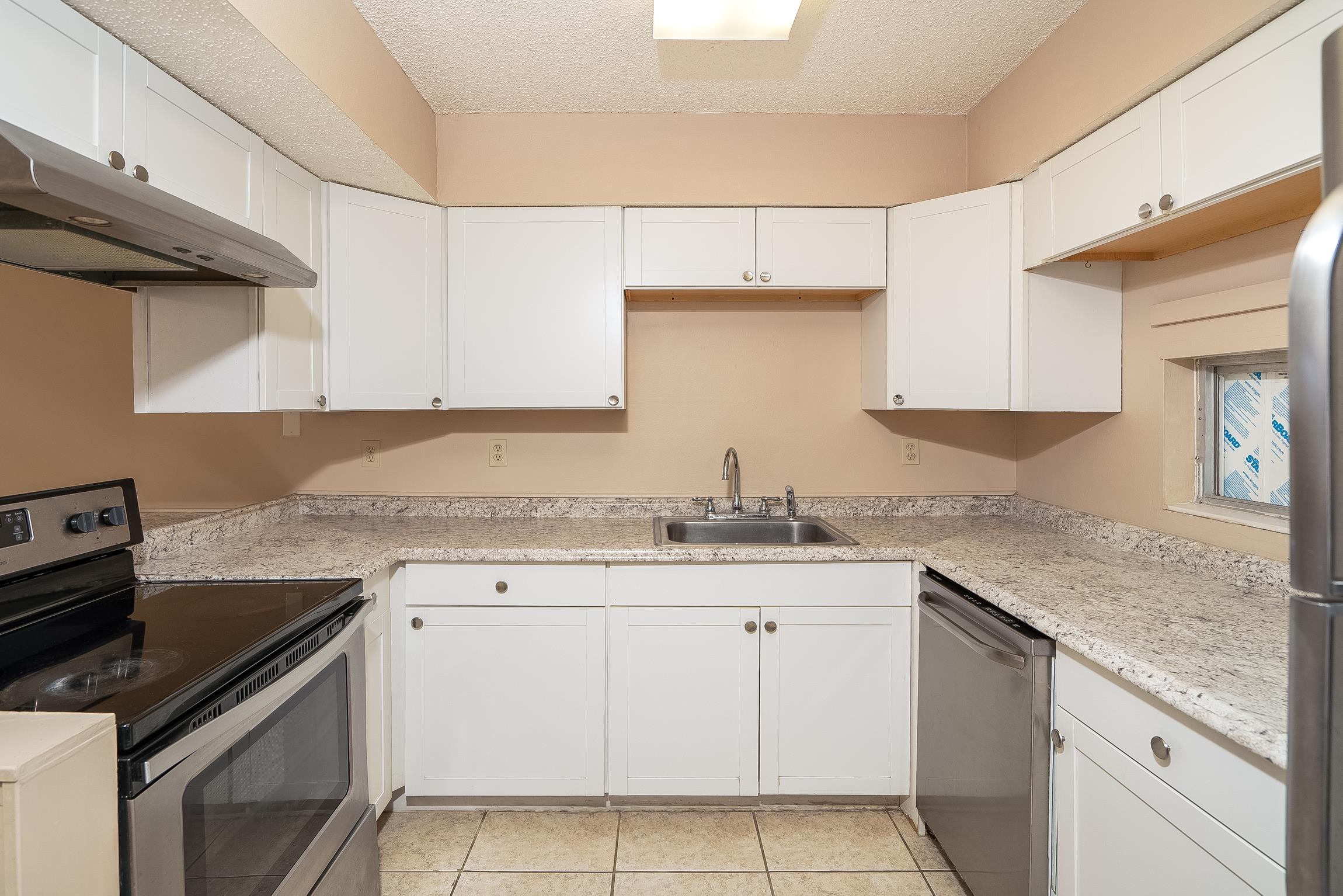 123 Rio Del Mar Street, Unit B St. Augustine, FL 32080 - Photo 22 of 51 a kitchen with granite countertop a sink stove and cabinets