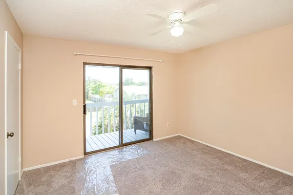 an empty room with windows and ceiling fan