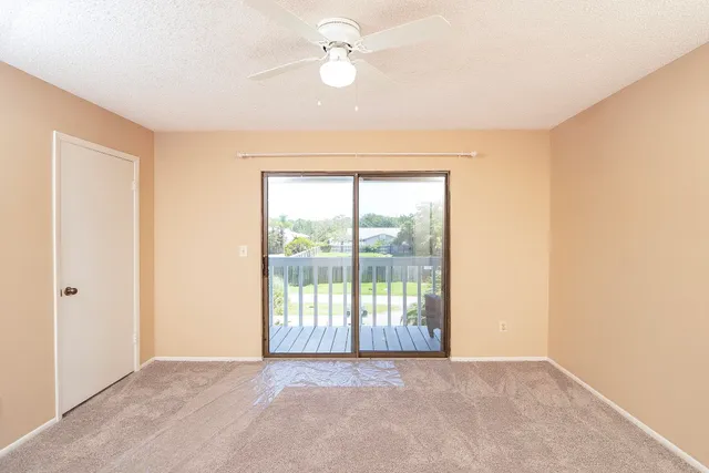 an empty room with chandelier fan and windows