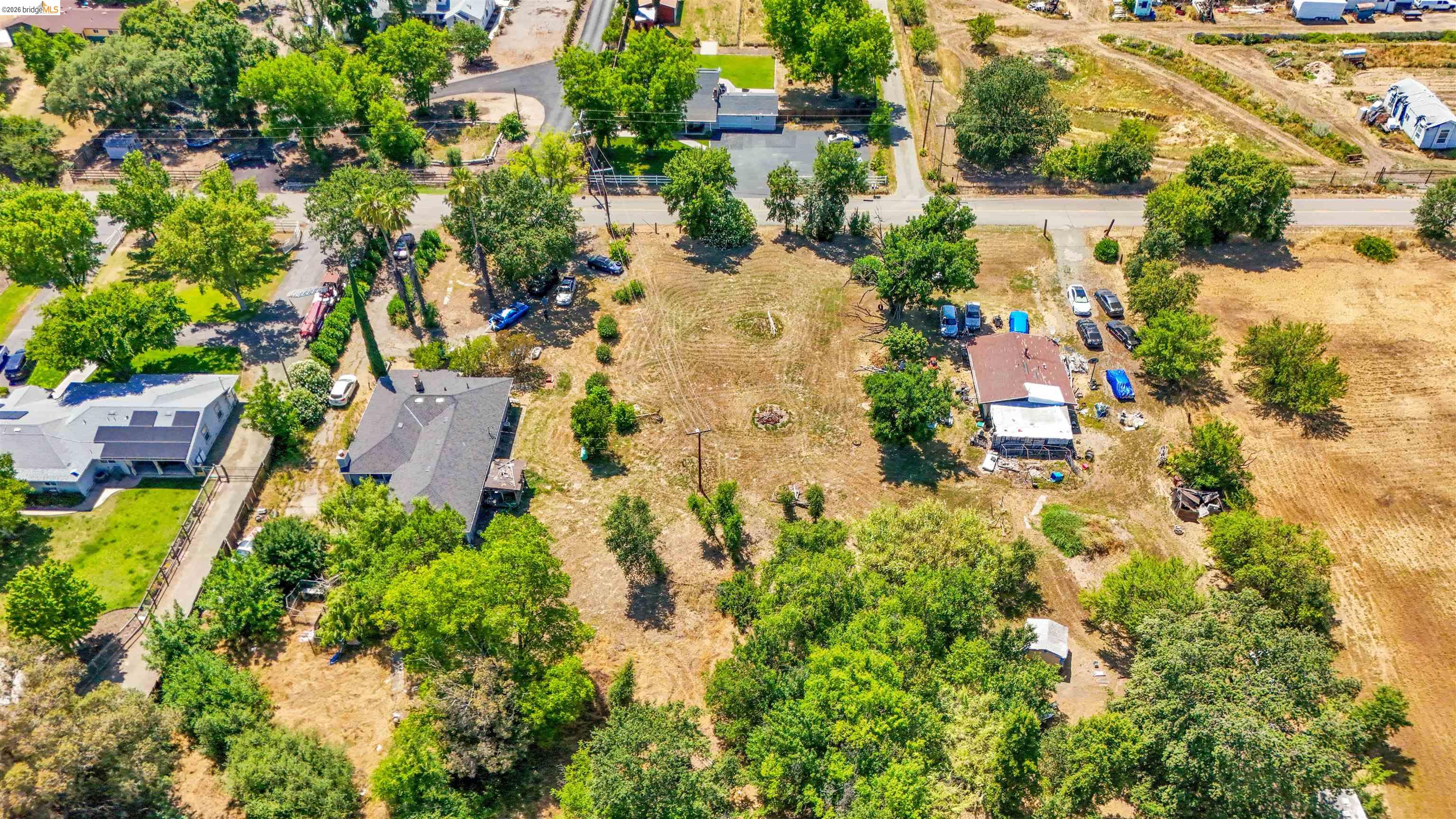 7750 Locke Road Vacaville, CA 95688 - Photo 9 of 23 Expansive cleared parcel surrounded by mature trees, featuring a visible power pole