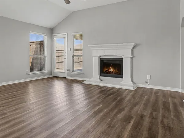 wooden floor fireplace and windows in an empty room
