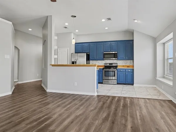 a large kitchen with stainless steel appliances granite countertop a refrigerator and a stove top oven