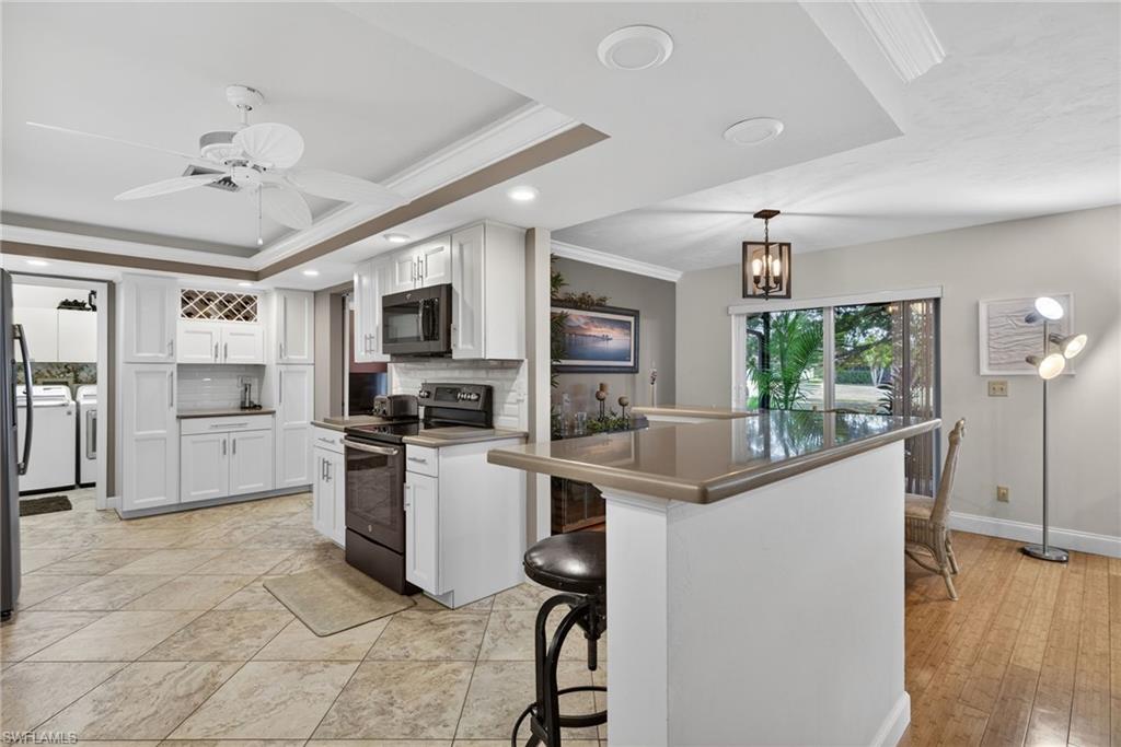 314 Reynolds Court Naples, FL 34112 - Photo 7 of 30 a kitchen with stainless steel appliances granite countertop a refrigerator a stove a sink a dining table and chairs with wooden floor