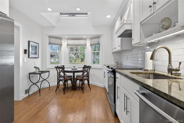 a kitchen with stainless steel appliances granite countertop a table chairs stove a sink dishwasher and cabinets with wooden floor