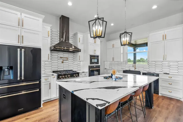 a kitchen with stainless steel appliances a stove a sink a refrigerator and wooden floor