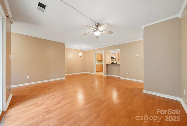 a view of empty room with wooden floor and ceiling fan