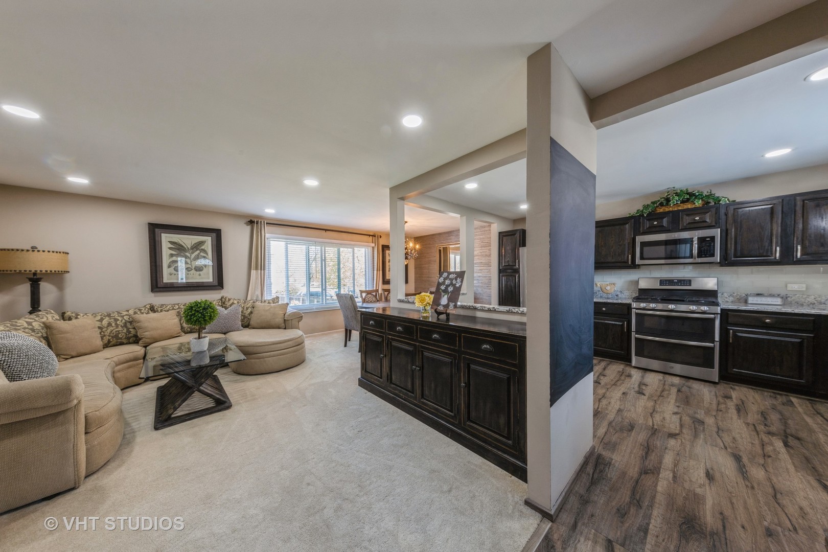 53 Wedgewood Road Matteson, IL 60443 - Photo 4 of 27 a large open kitchen with stainless steel appliances kitchen island granite countertop a refrigerator a stove a sink a dining table and chairs with wooden floor