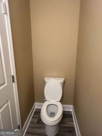 a white toilet sitting in a bathroom next to a wooden floor