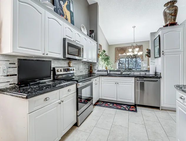 a kitchen with stainless steel appliances granite countertop a stove a sink and a white refrigerator