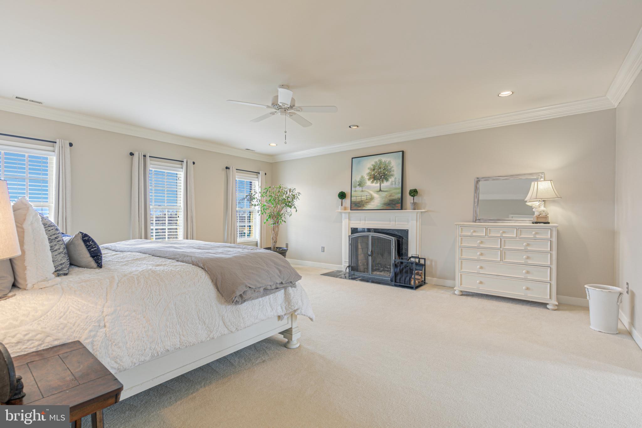 15140 Loyalty Road Waterford, VA 20197 - Photo 30 of 60 a spacious bedroom with a bed a fireplace and a couch