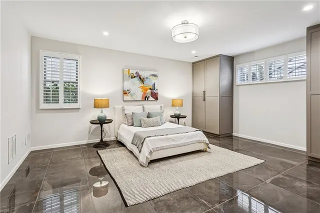 a bedroom with a bed painting on wall and windows