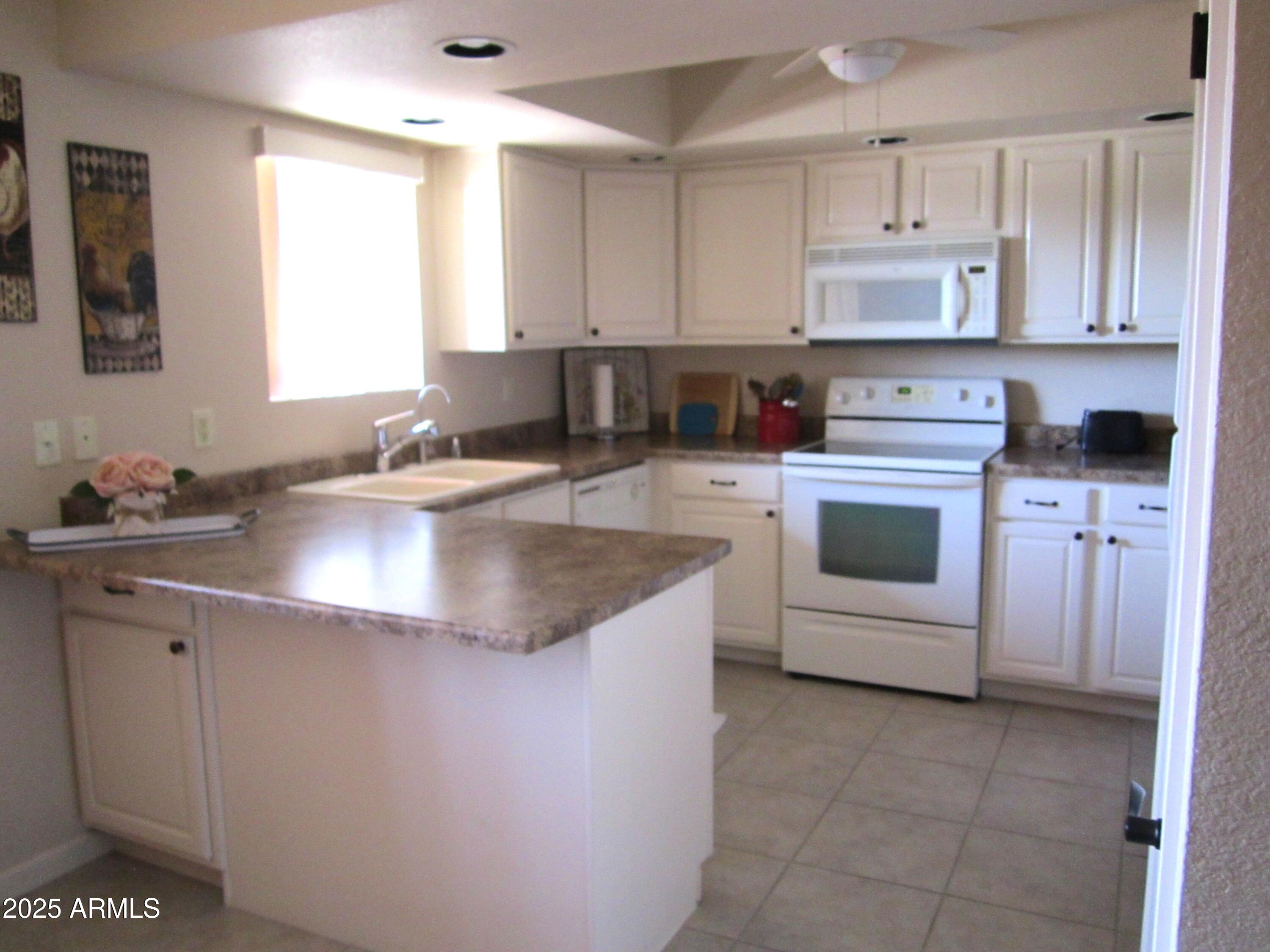 12222 North Paradise Village Parkway West, Unit 325 Phoenix, AZ 85032 - Photo 4 of 28 a kitchen with a sink a stove and cabinets