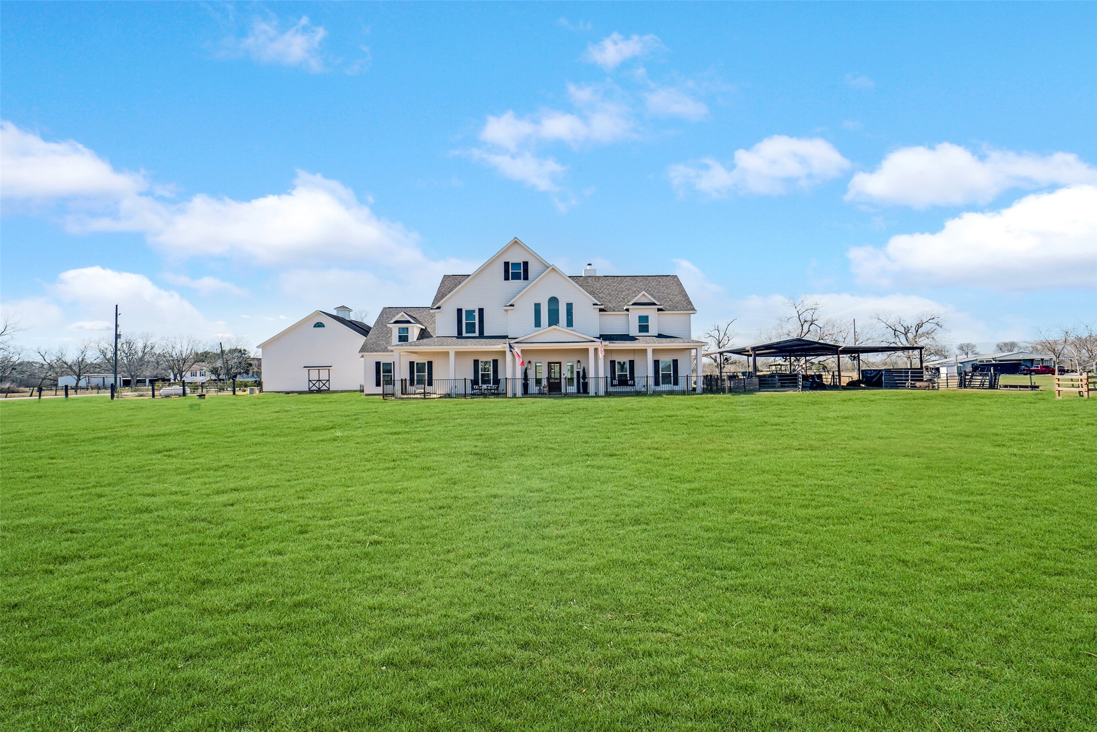 Expansive green acreage frames this charming farmhouse with wide open views.