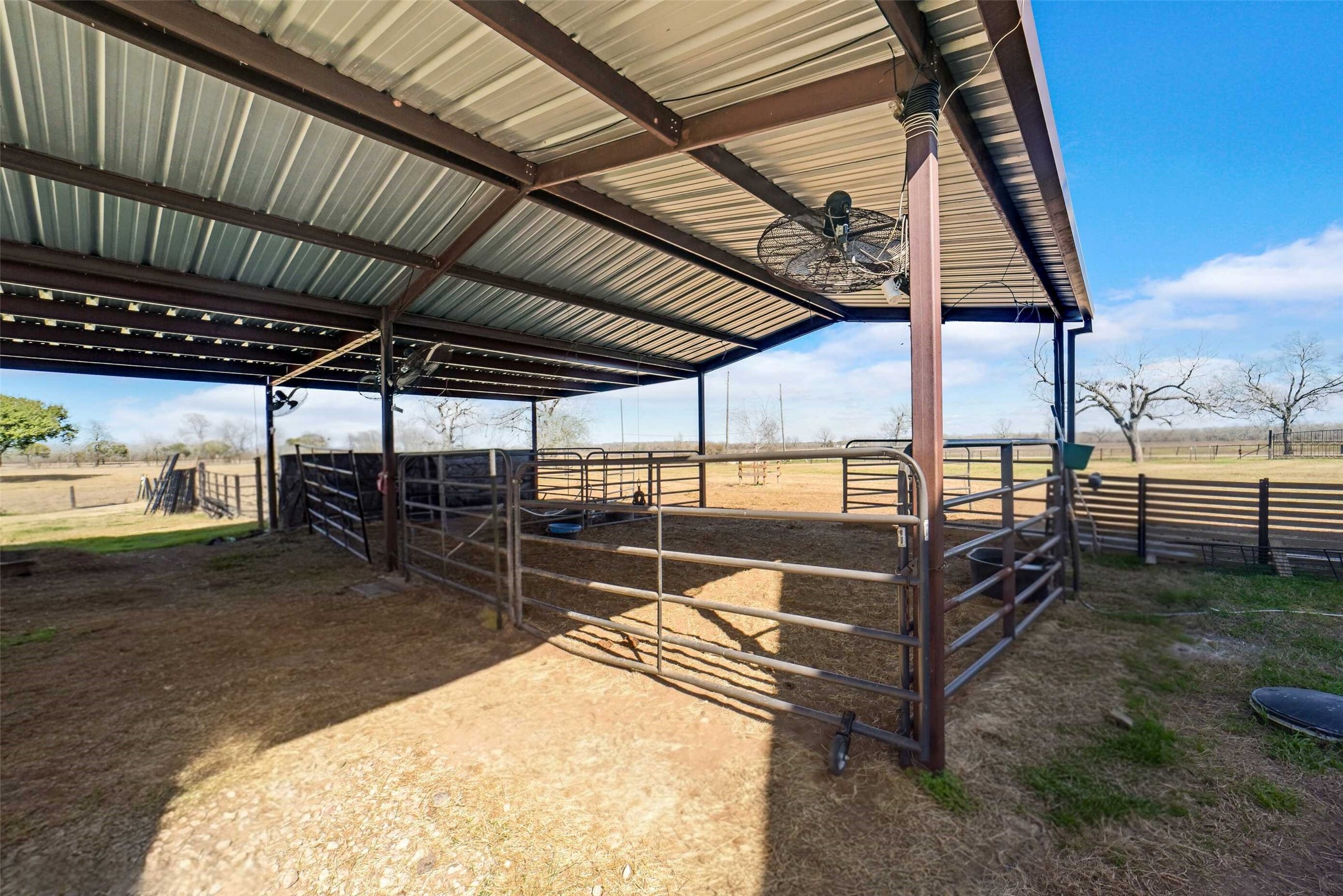 3103 Brundrett Road Wallis, TX 77485 - Photo 41 of 50 Covered livestock shelter with sturdy pipe fencing and wide-open pasture views, ideal for ranch living.