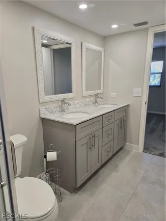 a bathroom with a double vanity sink a toilet and a tub