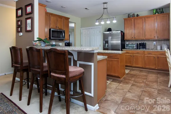 a kitchen with stainless steel appliances a dining table chairs microwave and sink