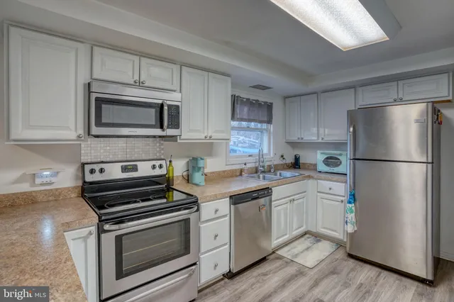 a kitchen with cabinets stainless steel appliances and wooden floor