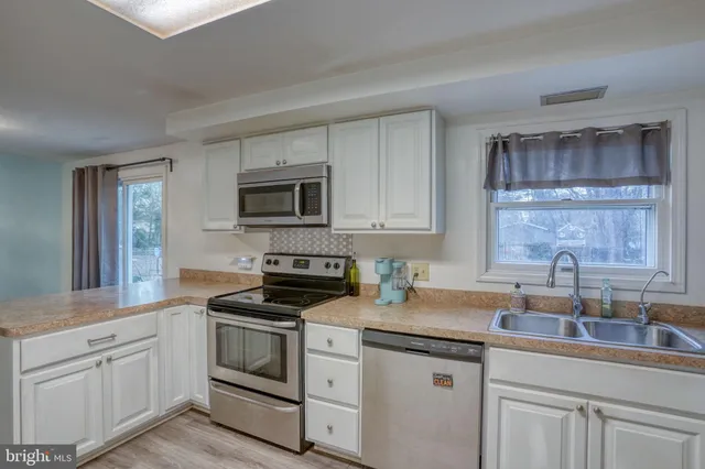 a kitchen with white cabinets appliances and a sink