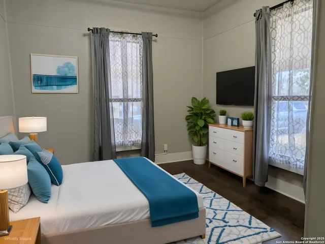 a bedroom with a bed television window and dresser