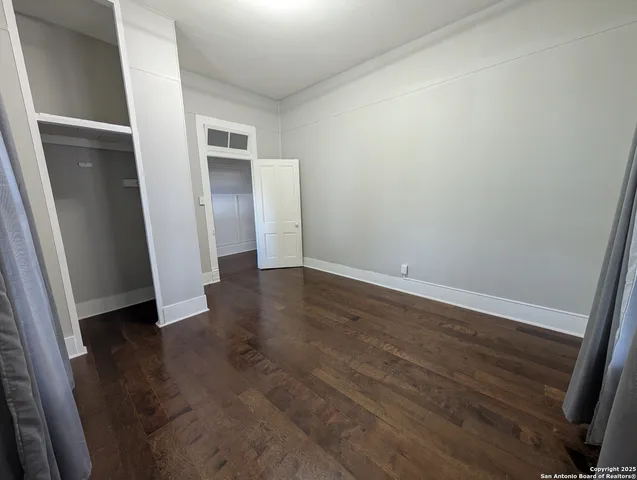 an empty room with wooden floor and entrance