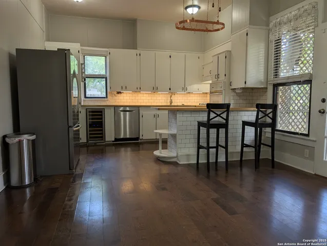 a kitchen with stainless steel appliances a dining table chairs and a refrigerator