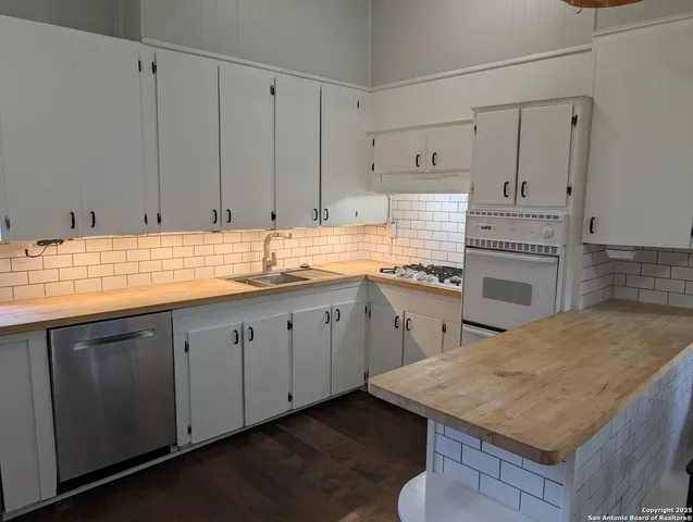 a kitchen with stainless steel appliances granite countertop a stove a sink and white cabinets