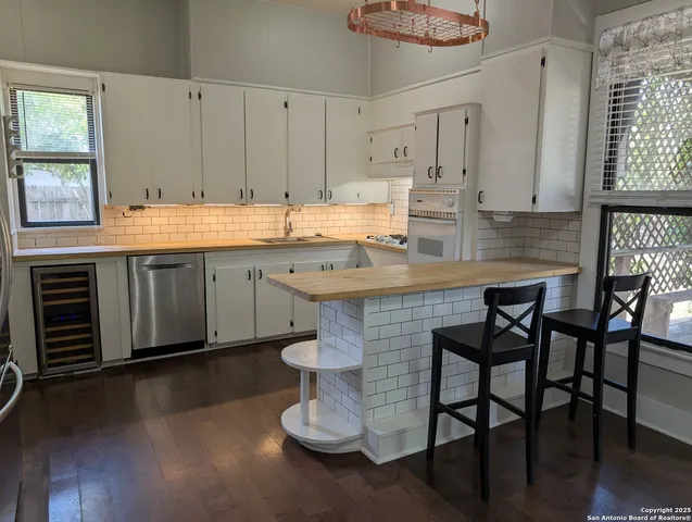 a kitchen with stainless steel appliances granite countertop a table chairs sink and cabinets