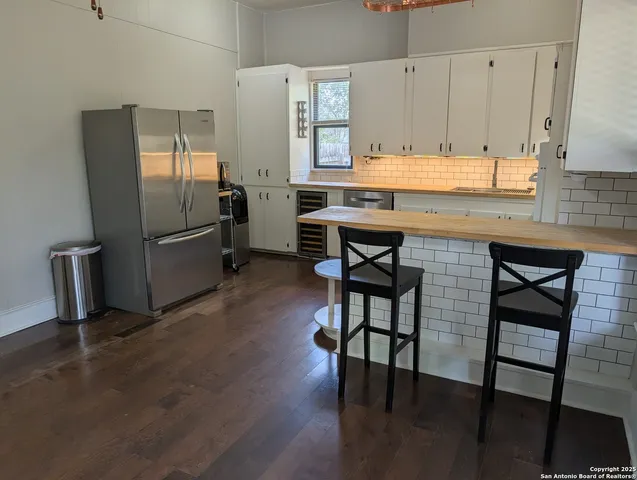 a kitchen with stainless steel appliances granite countertop a refrigerator a sink a stove and white cabinets