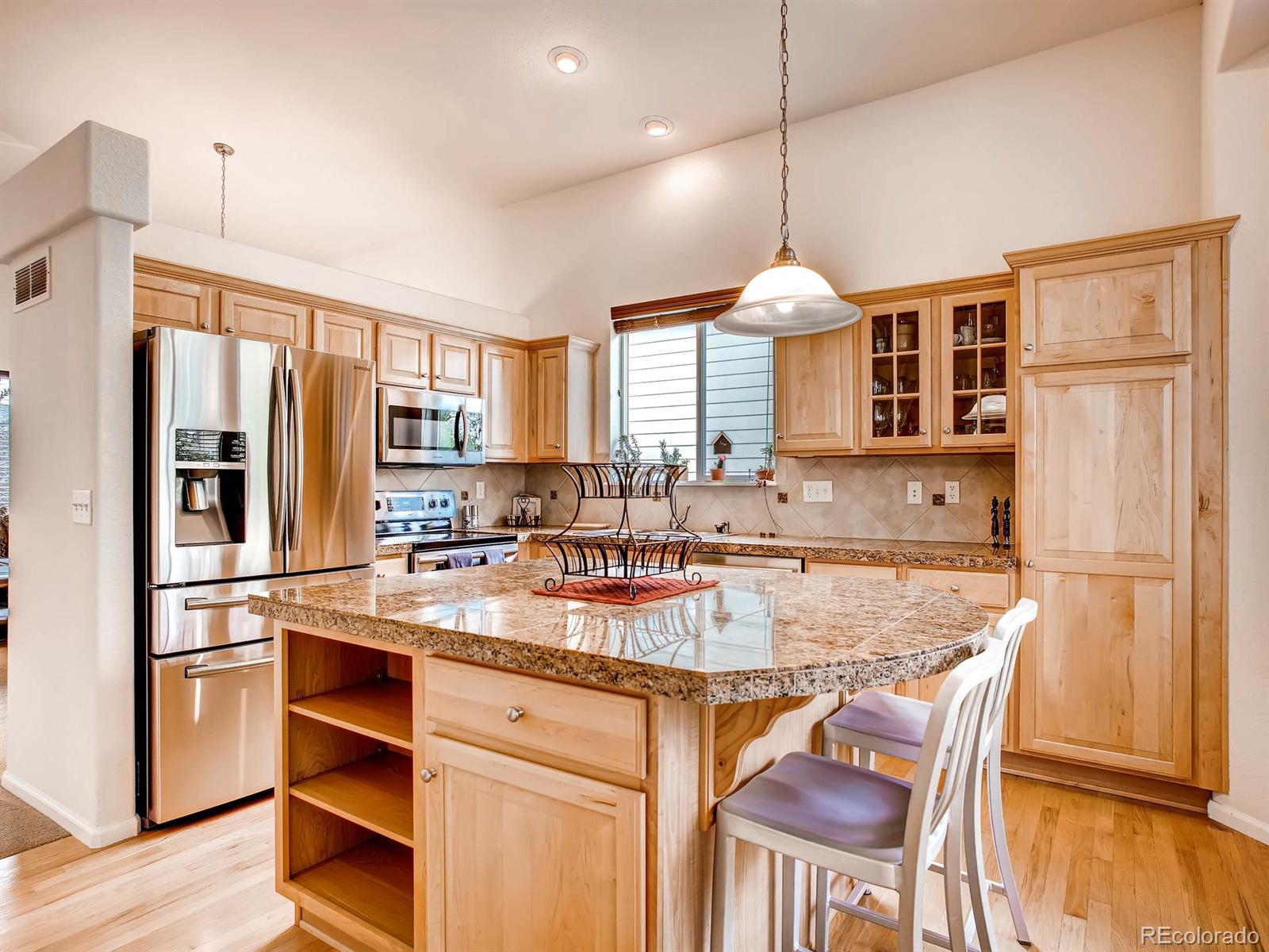10824 Towerbridge Road Highlands Ranch, CO 80130 - Photo 6 of 33 a kitchen with stainless steel appliances granite countertop a stove refrigerator and cabinets