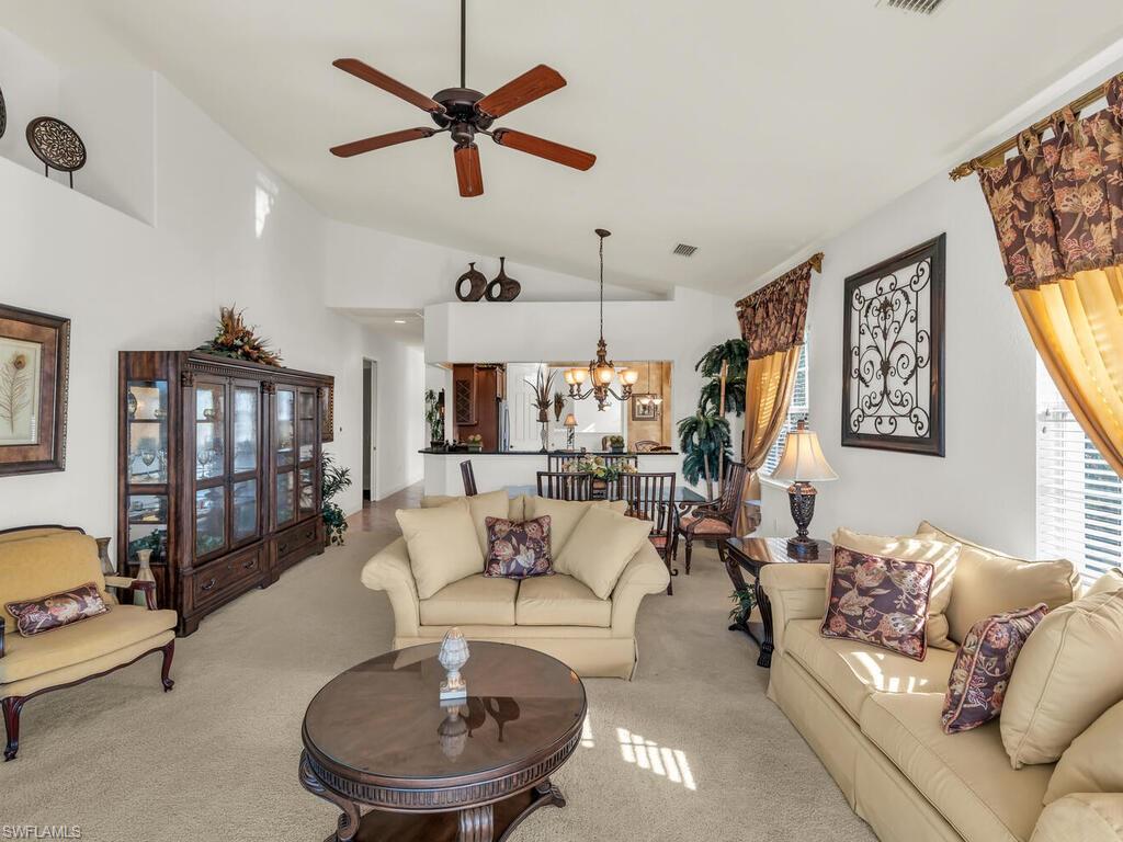 7869 Hawthorne Drive, Unit 303 Naples, FL 34113 - Photo 22 of 50 Living room with ceiling fan with notable chandelier, light colored carpet, and high vaulted ceiling