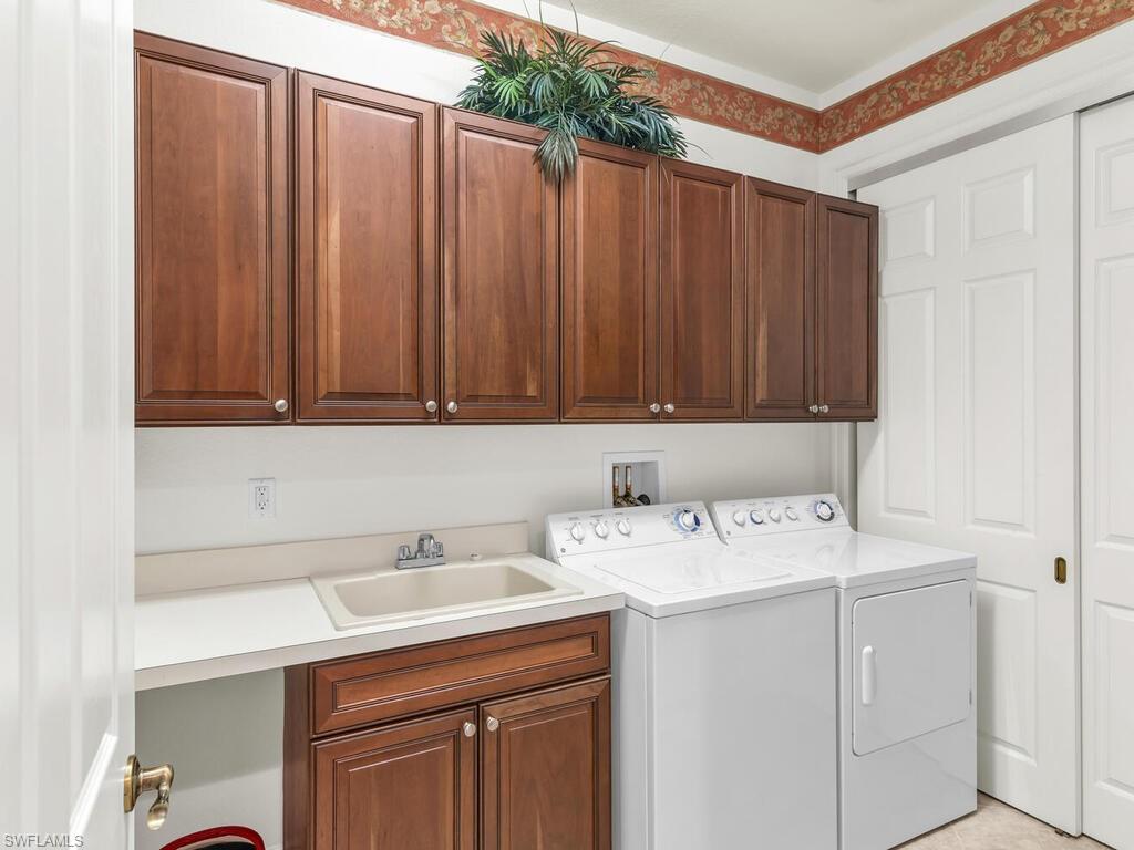 7869 Hawthorne Drive, Unit 303 Naples, FL 34113 - Photo 29 of 50 Clothes washing area featuring cabinets, sink, and washing machine and clothes dryer