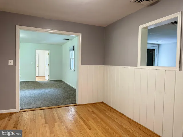 a view of a hallway with wooden floor and a bathroom