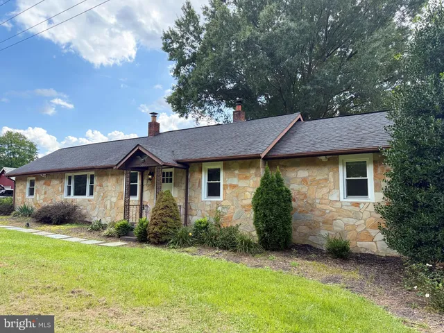 a view of a house with a yard plants and large tree