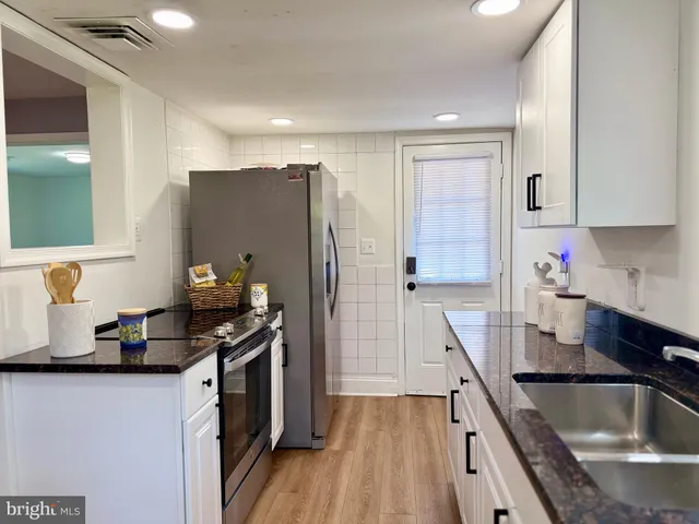 a kitchen with granite countertop a sink stove and refrigerator