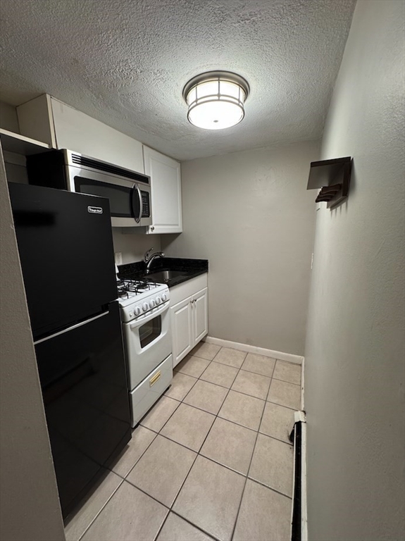 120 Charles Street, Unit 1 Boston, MA 02114 - Photo 1 of 4 a kitchen with stainless steel appliances a refrigerator a stove and white cabinets