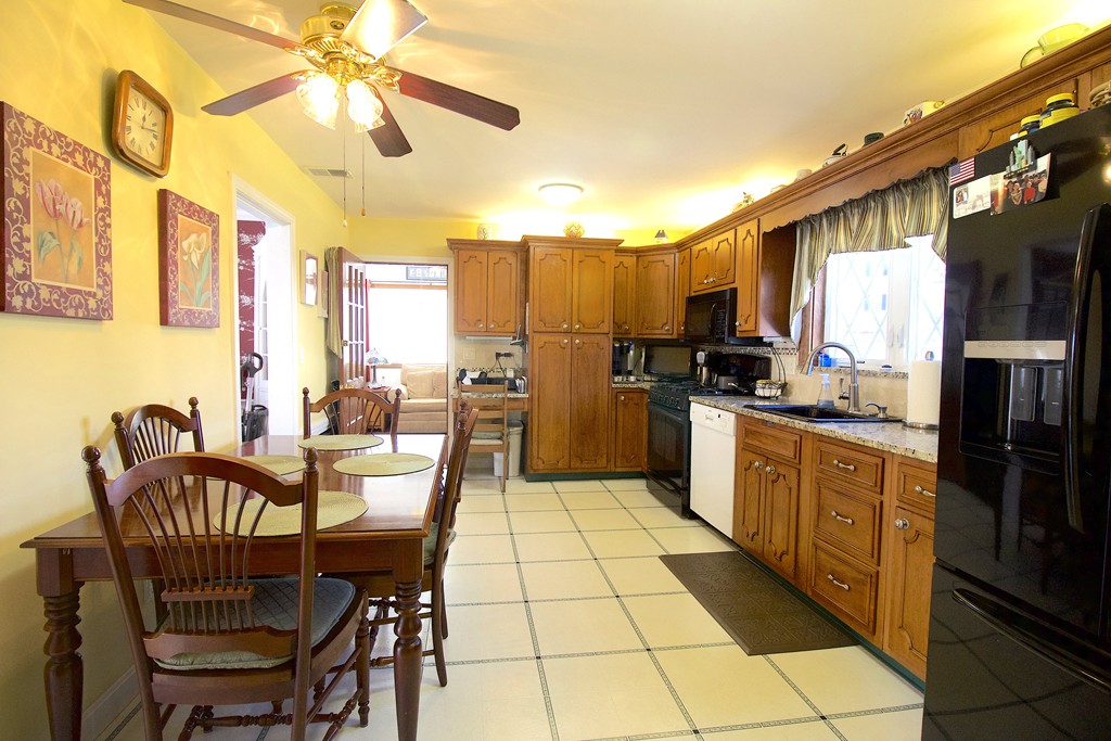 41 Lodge Road Newton, MA 02465 - Photo 6 of 25 a kitchen with stainless steel appliances granite countertop a refrigerator a stove a kitchen island with a dining table and chairs