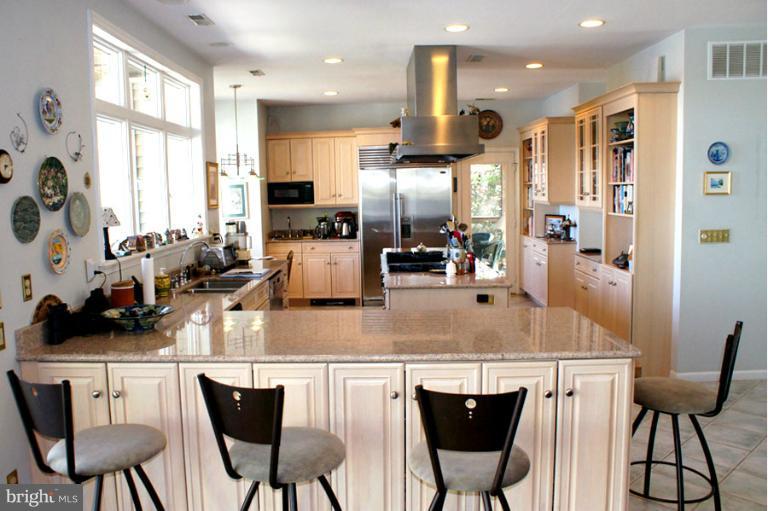 1421 Oak Bluff Road Edgewater, MD 21037 - Photo 13 of 30 a kitchen with stainless steel appliances kitchen island granite countertop a table chairs and a refrigerator