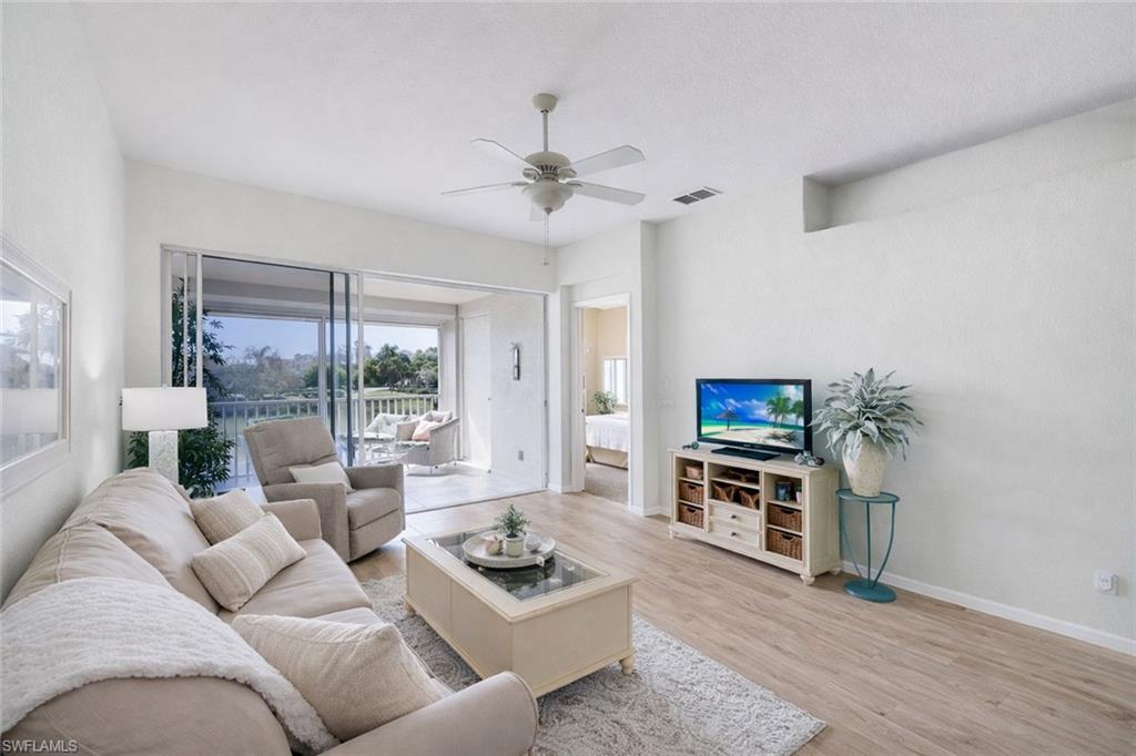 10801 Halfmoon Shoal Road, Unit 202 Estero, FL 34135 - Photo 3 of 45 (Virtual wall color change and flooring upgrades) Living room with gorgeous view of of the lake and fountains with a western facing view.
