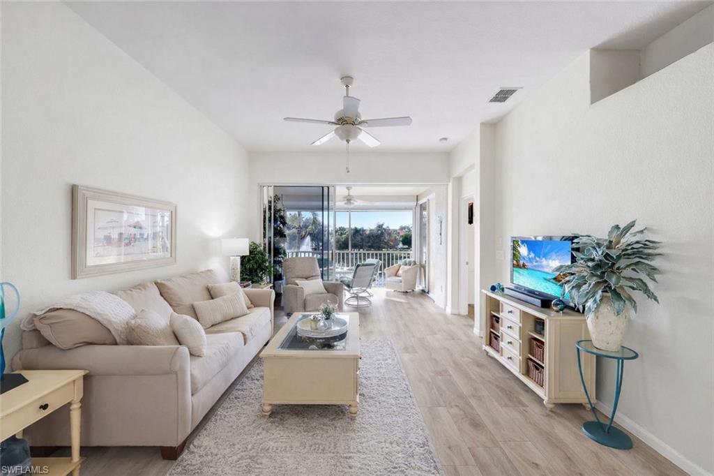 10801 Halfmoon Shoal Road, Unit 202 Estero, FL 34135 - Photo 4 of 45 (Virtual wall color change and flooring upgrades) Living room with gorgeous view of of the lake and fountains with a western facing view.