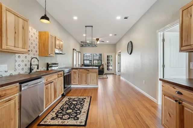 a large kitchen with stainless steel appliances granite countertop a refrigerator a sink dishwasher a stove and white countertops with wooden floor