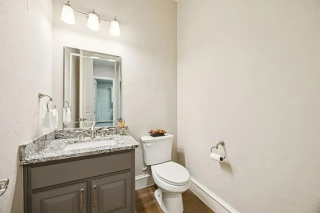 a bathroom with a granite countertop sink toilet and mirror