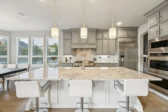 a kitchen with kitchen island granite countertop a view of living room and stainless steel appliances