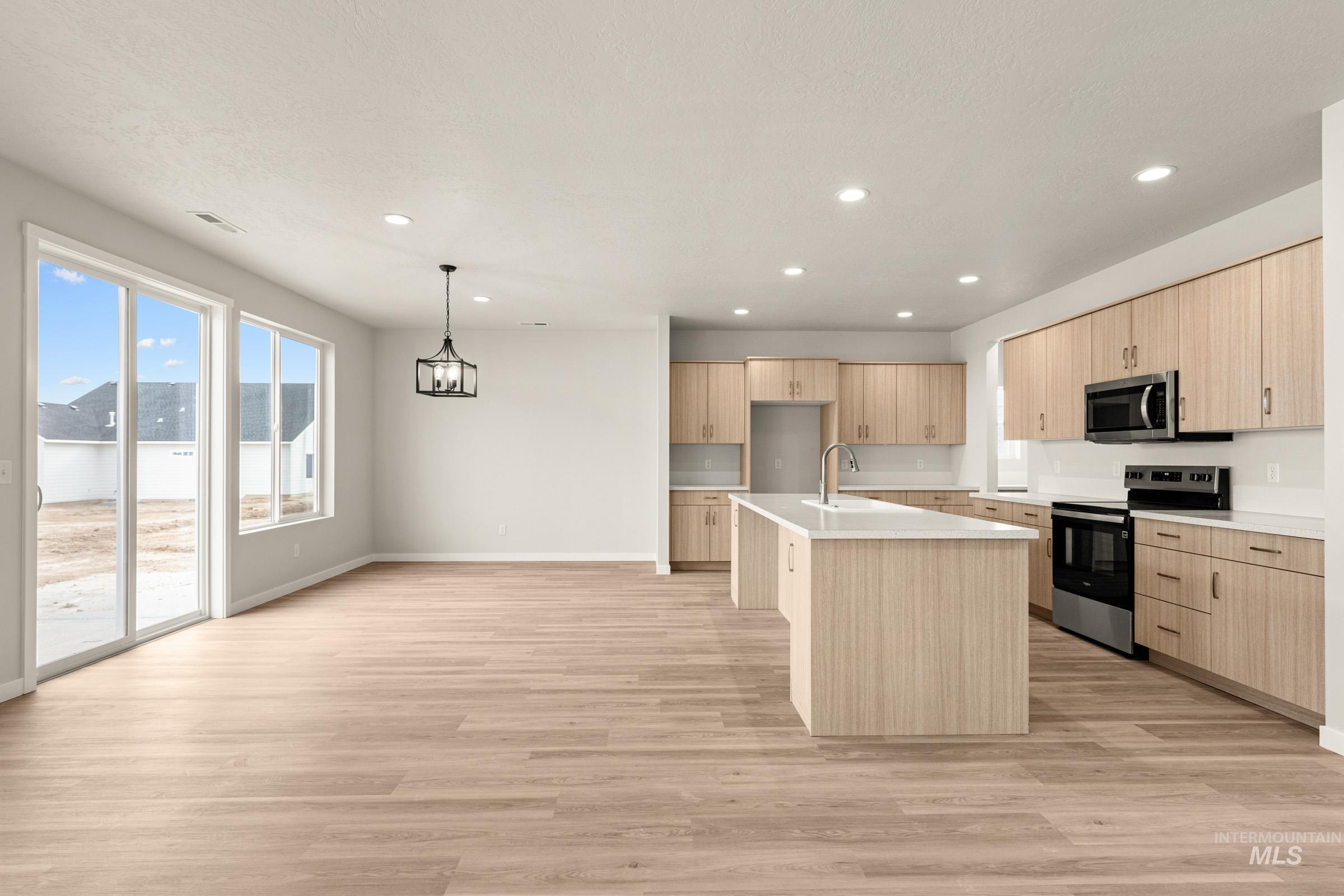 13688 Redway Court Caldwell, ID 83607 - Photo 5 of 26 Kitchen with a kitchen island with sink, stainless steel appliances, light wood finish cabinets, light countertops, and light wood finished floors