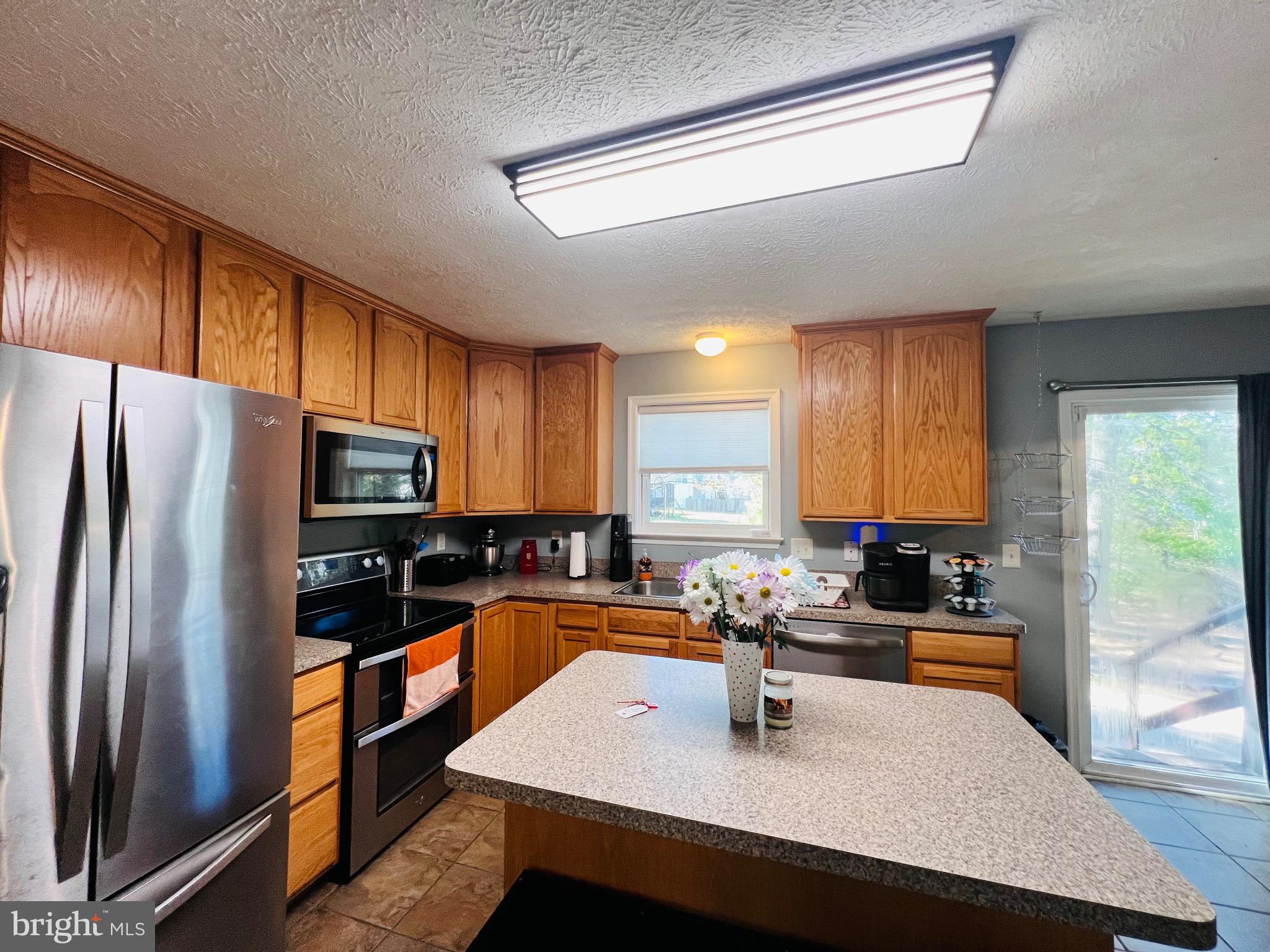 213 Forest Avenue Colonial Beach, VA 22443 - Photo 18 of 54 a kitchen with a sink a counter top space cabinets stainless steel appliances and a window