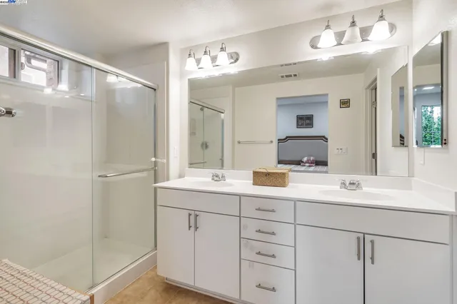 a bathroom with a double vanity sink mirror and shower