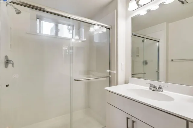 a bathroom with a granite countertop sink mirror and a shower
