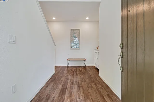 a view of a hallway with wooden floor and a bathroom