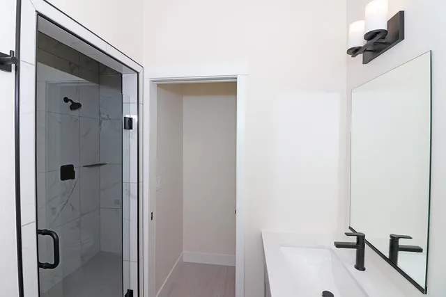 a bathroom with a granite countertop sink a mirror and shower