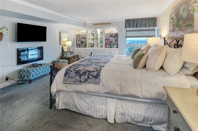 a bedroom with a large bed and a flat tv screen on dresser